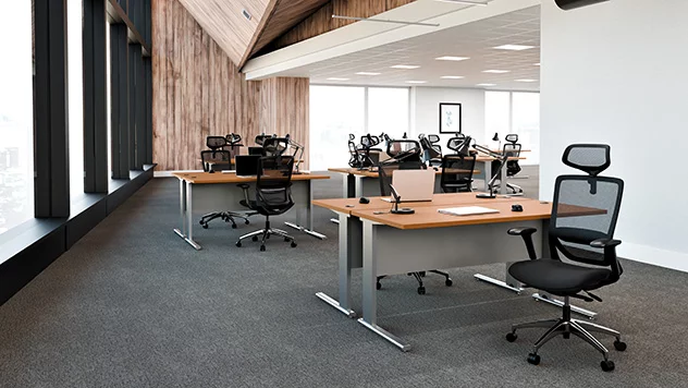 Krzesło wykonane z białej siatki zostało ustawione przy stanowisku pracy w tożsamym kolorze. W tle - duże okna z żaluzjami.